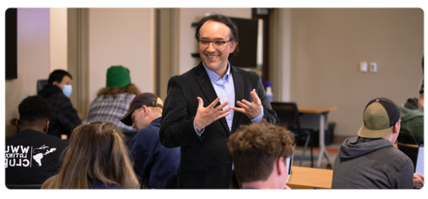 A business professor talks animatedly with students